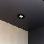 Black adjustable recessed spotlight installed in a dark cabinet ceiling