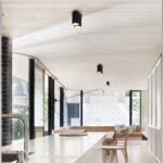Black surface mount cylinder downlights installed along white ceiling in modern dining area
