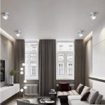 White rotatable LED ceiling spotlight installed in modern living room, surface-mounted adjustable spotlight for ambient and accent lighting