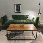 Smoky grey glass ball pendant wall light beside a green sofa