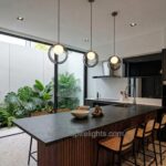 Three smoky grey glass ring pendant lights above a black kitchen island